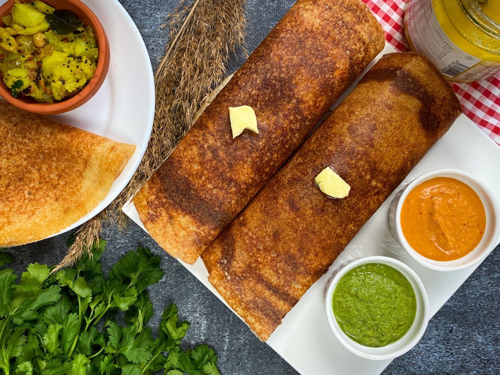 Dosas served overhead with potato masala, coconut and mint chutneys