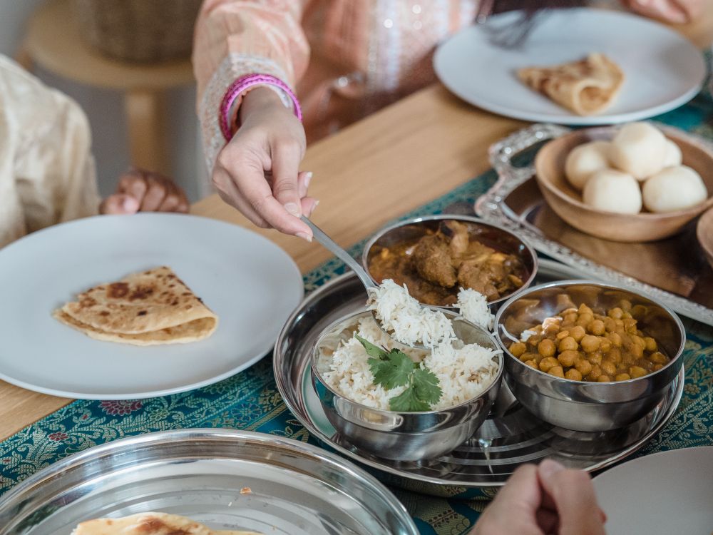 Guests in traditional Indian dress sharing a vegetarian meal of rice, chole, parathas and rasgulla